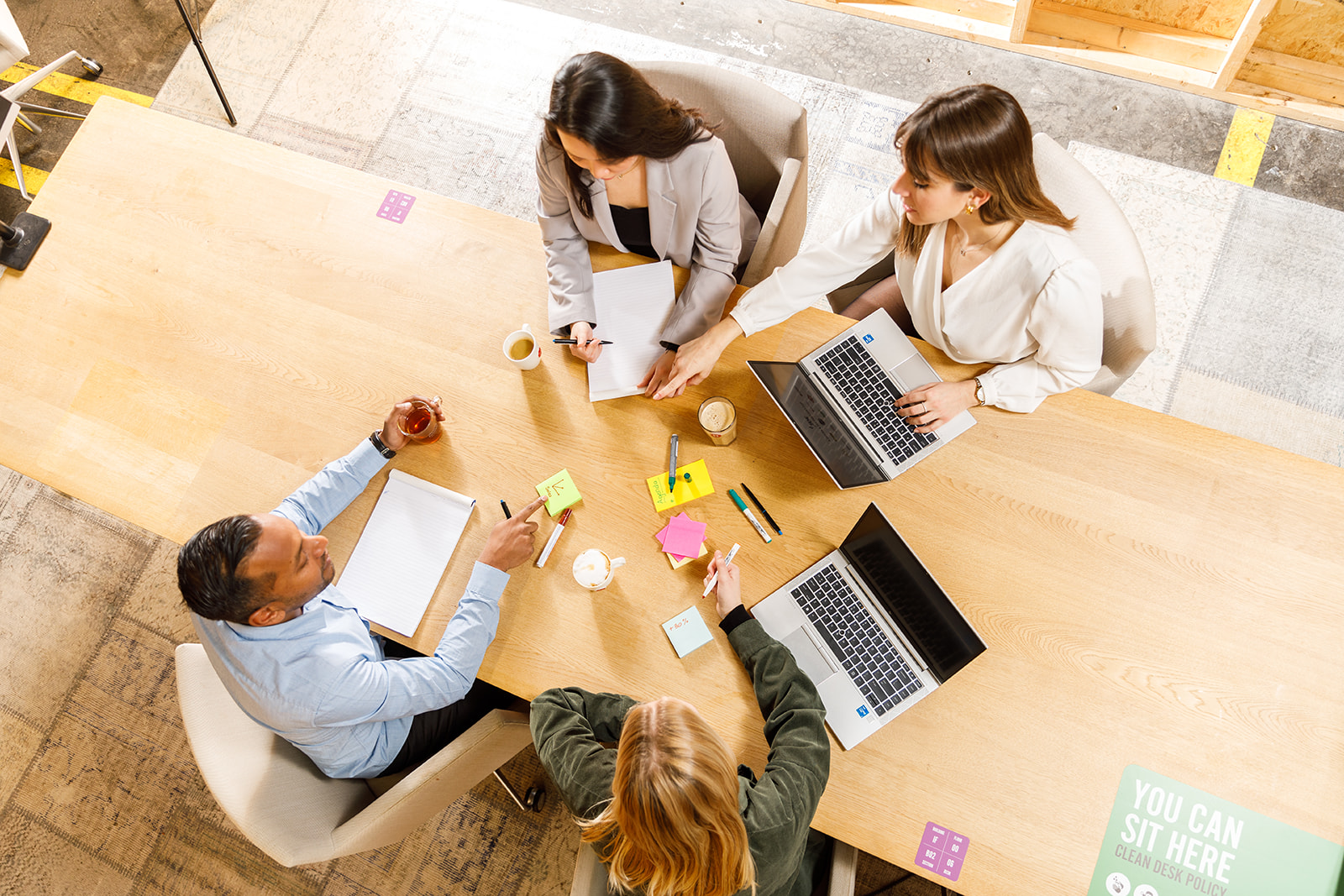 Quatre collègues travaillent ensemble autour d'une table avec leurs ordinateurs portables et leurs notes.